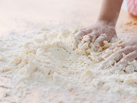 Kid's hands mixing flour and egg on table, to processing dough and lifestyle concept.の写真素材