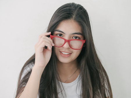 Beautiful Asian teenager girl holding red eyeglasses and look at camera, lifestyle concept.の写真素材