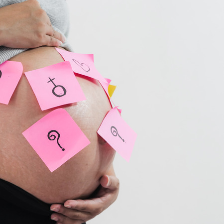 Body part pregnant belly with pink sticky notes on white background.の写真素材