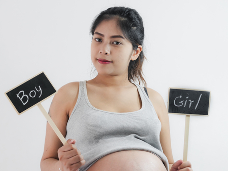 Happy Asian pregnant woman showing boy or girl blackboard, lifestyle concept.の写真素材