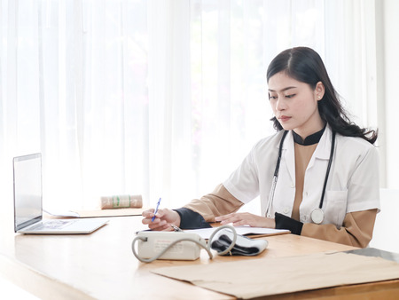Female Asian doctor working at office desk, lifestyle concept.