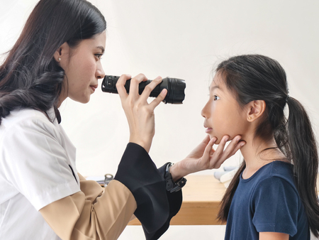 doctor wear white coat shines a flashlight to the patient's eyes at the clinic. concept of Healthcare, Medical treatmentの写真素材
