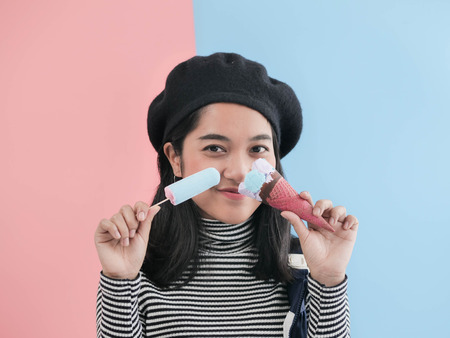 Happy Asian woman eating blue ice cream stick with color background.