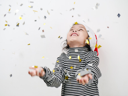 Happy Asian girl celebrating with silver and golden papers glitter falling down