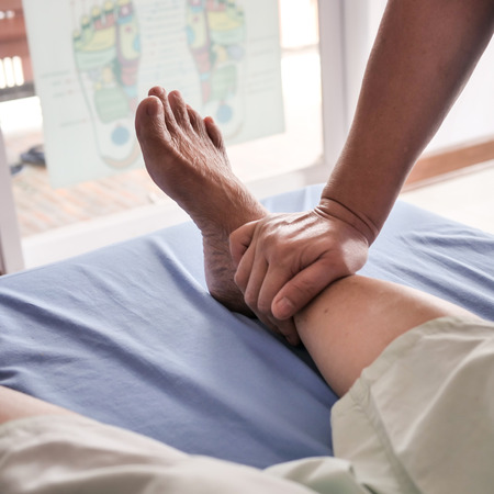 Senior lady having body and legs massage by therapist.の写真素材
