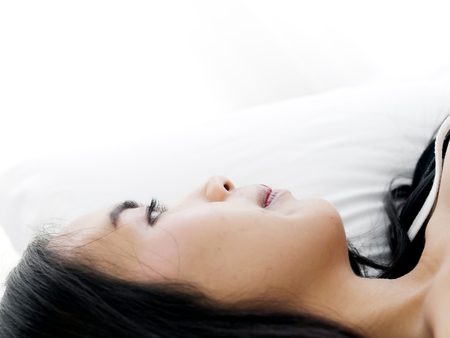 Happy Asian woman lying on bed, closed up with copy space.