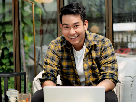 Happy Asian man working with laptop in cafe, work concept.の写真素材