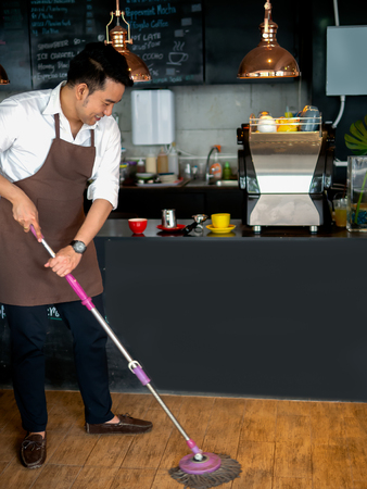 Asian barista cleaning floor in cafe.の写真素材