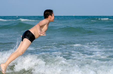 Asian preteen boy jumping into the sea, summer concept.の写真素材