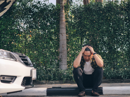 Stressed Asian man with car problem and sitting on pathway and cry, lifestyle concept.