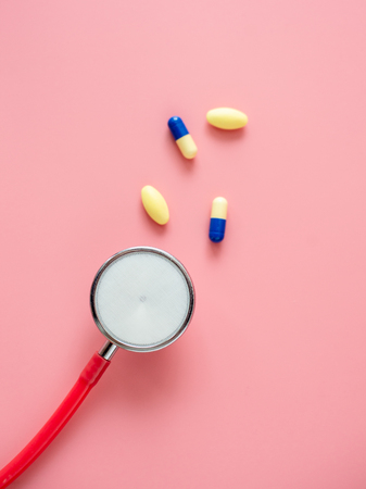 Red Stethoscope and pill capsule on pink background.の写真素材