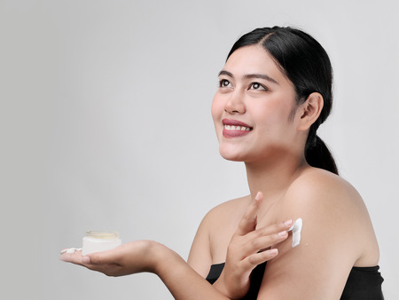 Beauty portrait of Asian smile beautiful woman applying moisturizer cream on her shoulder.の写真素材