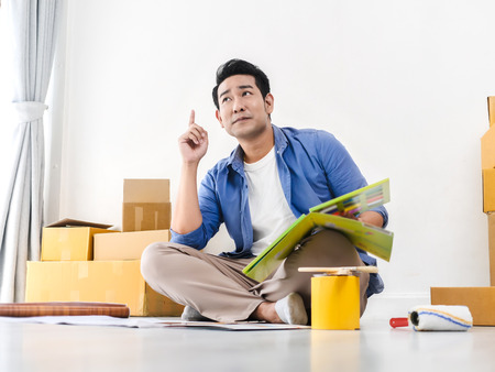 Happy Asian man choosing color palette for his new house.の写真素材