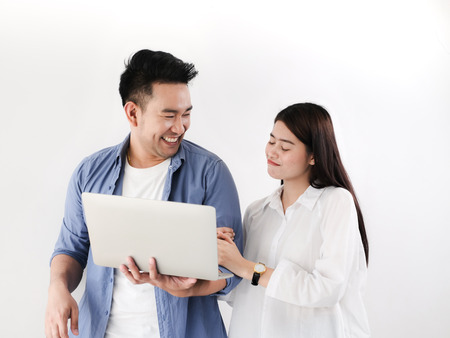 Happy Asian couple shopping online with holding credit card and laptop and sitting at home together,...