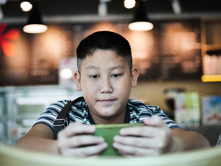 Asian boy using smartphone in coffee shop, lifestyle concept.の写真素材