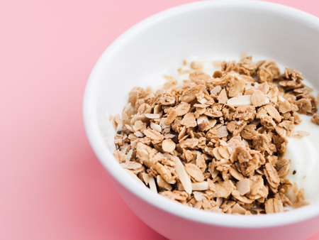 Whole grains on yogurt in white bowl, pink background.の写真素材