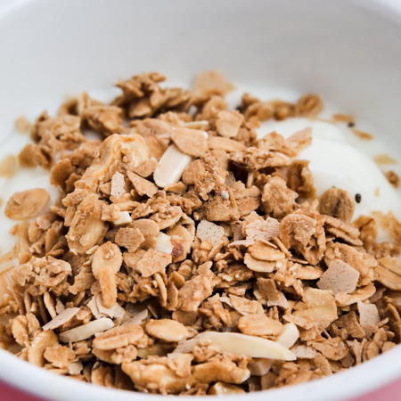 Whole grains on yogurt in white bowl, pink background.の写真素材