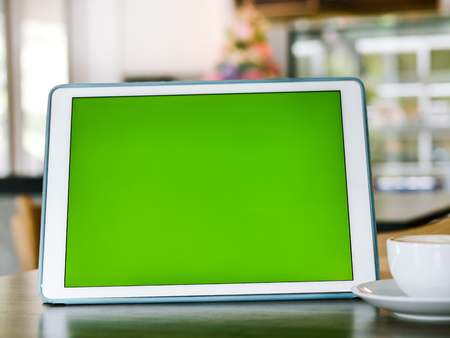 Green screen tablet and coffee mug on table, mock up.の写真素材