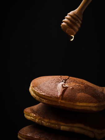 Pancake with honey syrup dipper and black background.の写真素材
