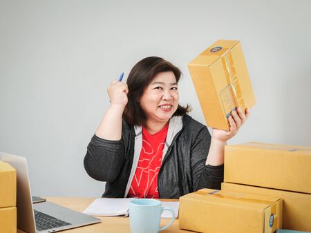 Fat Asian woman packing goods for selling online, delivery concept.