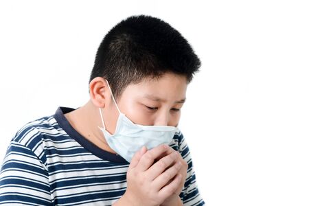 Asian sick young preteen boy with face mask on, boy coughing inside mask on white background.の写真素材