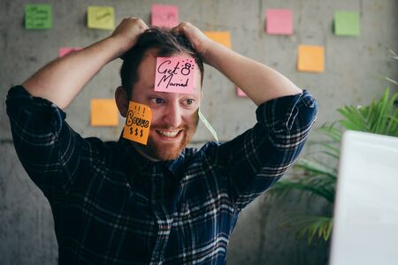 Stressed man with message on sticky notes over his face in office.の写真素材