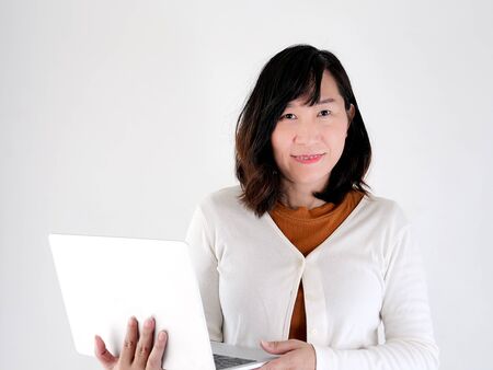 Happy Asian woman using laptop against the wall, lifestyle concept.の写真素材