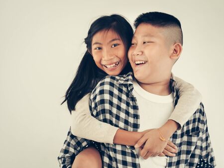 Happy Asian pretty girl enjoying riding on her brother piggyback, lifestyle concept.の写真素材