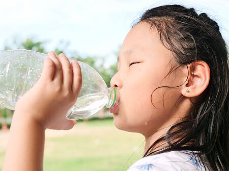 Asian girl drinking a bottle of water outdoor.の写真素材