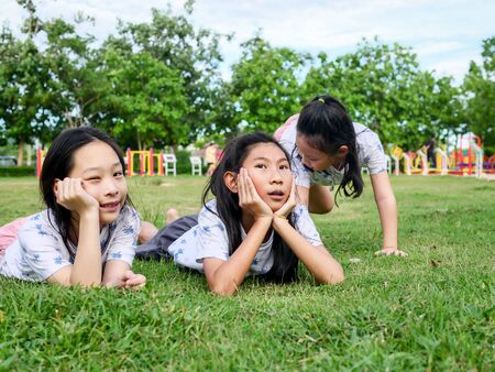 Happy Asian girls laying down on green grass outdoor together, lifestyle concept.の写真素材