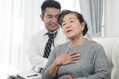 Asian doctor checking up his patient old woman in office.の写真素材