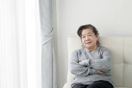 Happy Asian senior woman relaxing on sofa at home, lifestyle concept.の写真素材