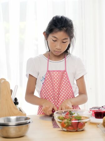 Asian girl learing to decorationg cupcake at home, lifestyle concept.の写真素材