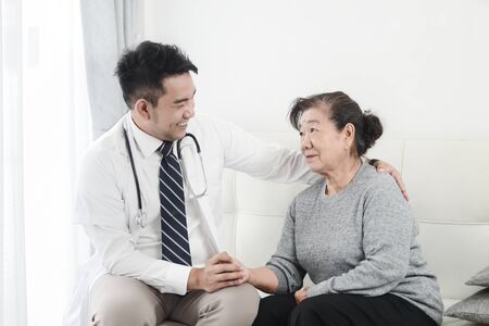 Asian doctor checking up his patient old woman in office.