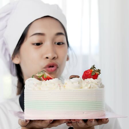 Happy Pastry chef showing her homemade cake in her hand, lifestyle concept.