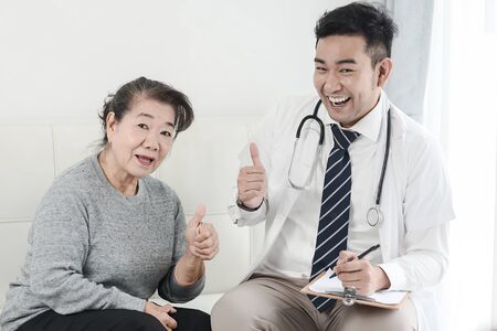 Asian doctor and senior patient with thumbs up hands sign, health care concept.の写真素材