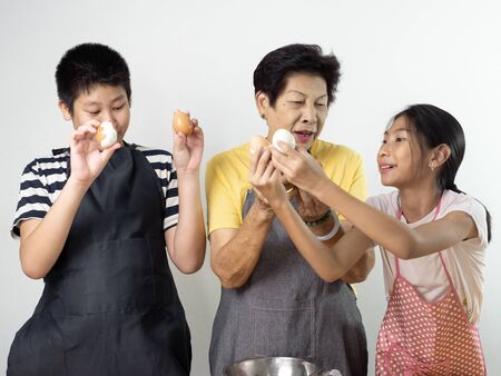 Asian senior woman teaching her grandchildren  peeled eggs, lifestyle concept.の写真素材