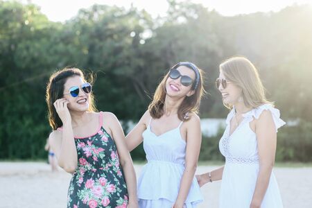 Happy Asian women wearing long dress and standing on the beach together, lifestyle concept.