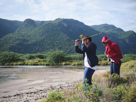 Happy Asian couple fishing together with nature background, lifestyle concept.