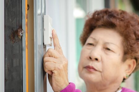Asian senior woman clicking door bell, lifestyle concept.の写真素材