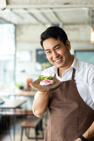 Happy Asian man present homemade valentine cookie at home.の写真素材