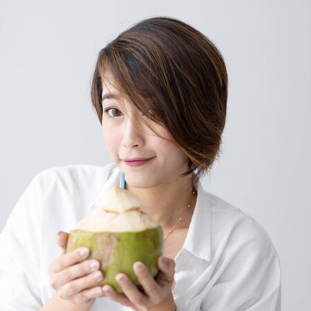 Asian cute girl relax with coconut  drink in white room, lifestyle concept.の写真素材