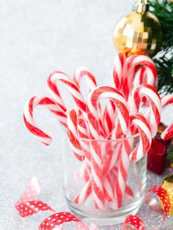 Christmas candy sticks on glass with silver bokeh background.の写真素材