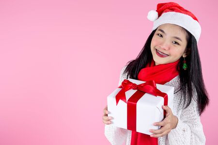 Happy Asian teenager girl holding gift boxes on pink  background.の写真素材