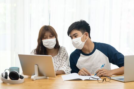 Asian teenager using  laptop and tablet for online schooling from home together, quarantine concept.
