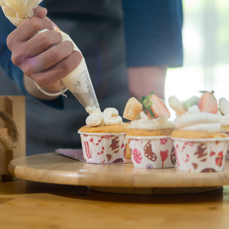 Asian teenager boy decorating cupcakes at home, lifestyle concept.の写真素材