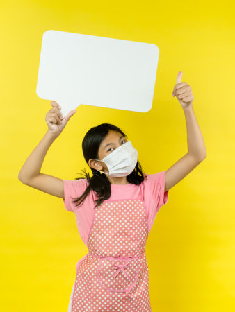 Asian girl showing blank speech bubble on yellow background.の写真素材