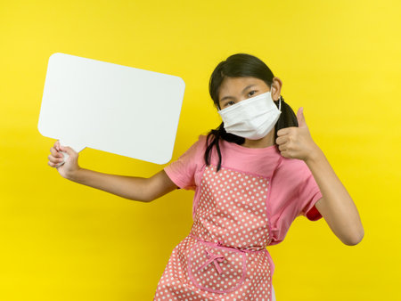 Asian girl showing blank speech bubble on yellow background.の写真素材
