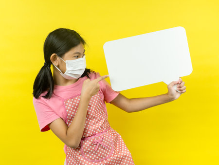 Asian girl showing blank speech bubble on yellow background.の写真素材