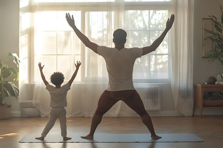 Back view of father and son doing yoga together at home. Father and son exercising together at morning.の素材